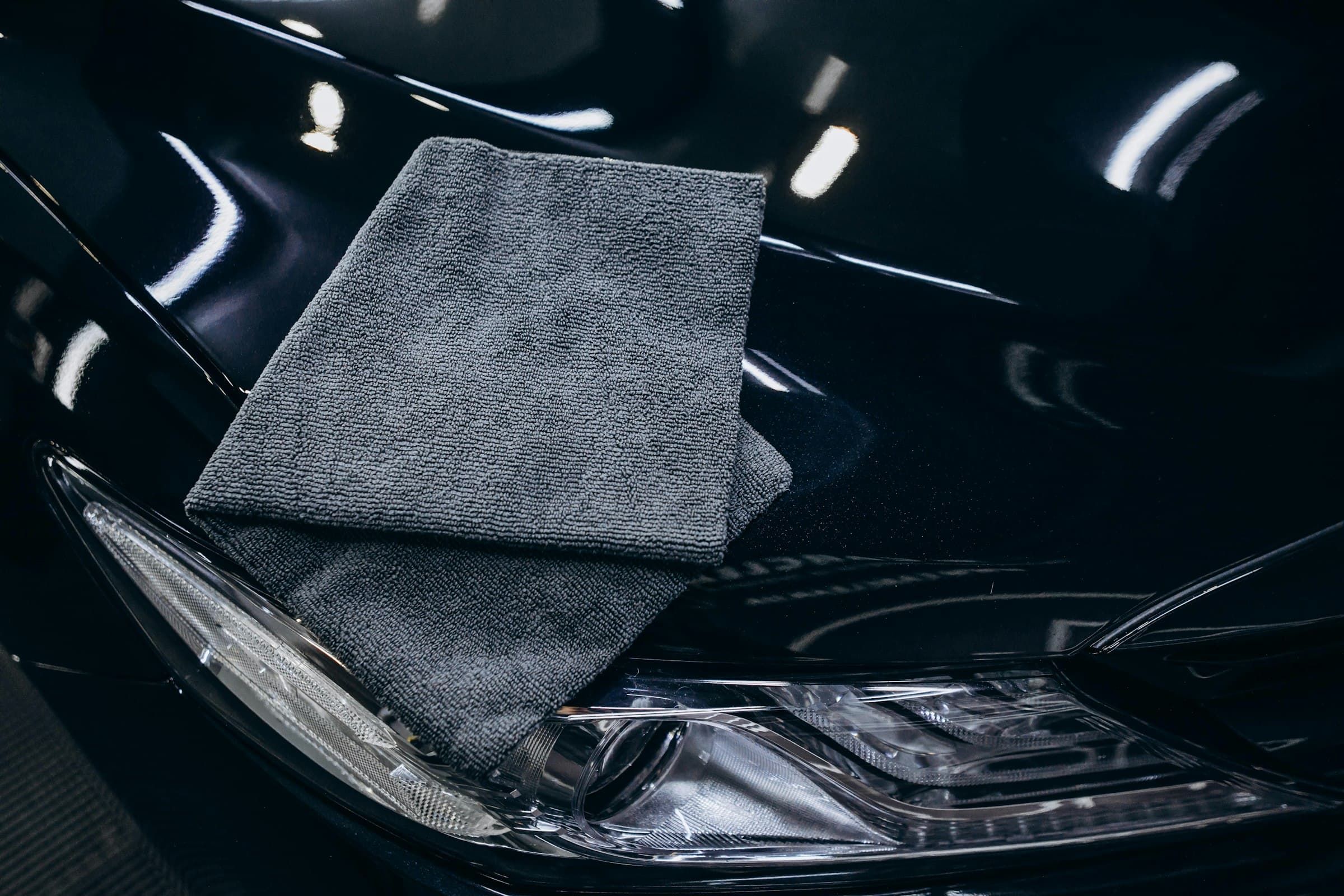 A microfibre cloth resting on the polished bonnet of a black car